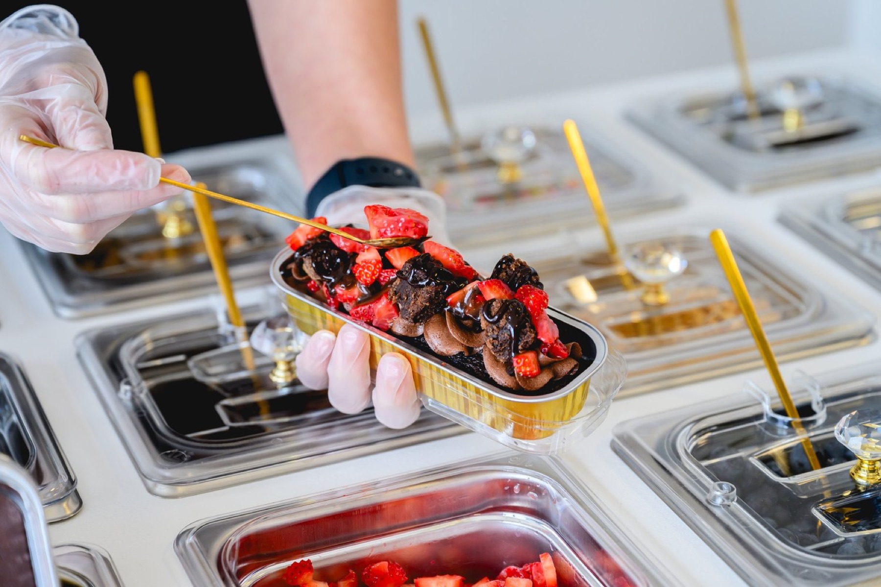 A Lalou Desserts associate assembling a fresh dessert with strawberries and chocolate